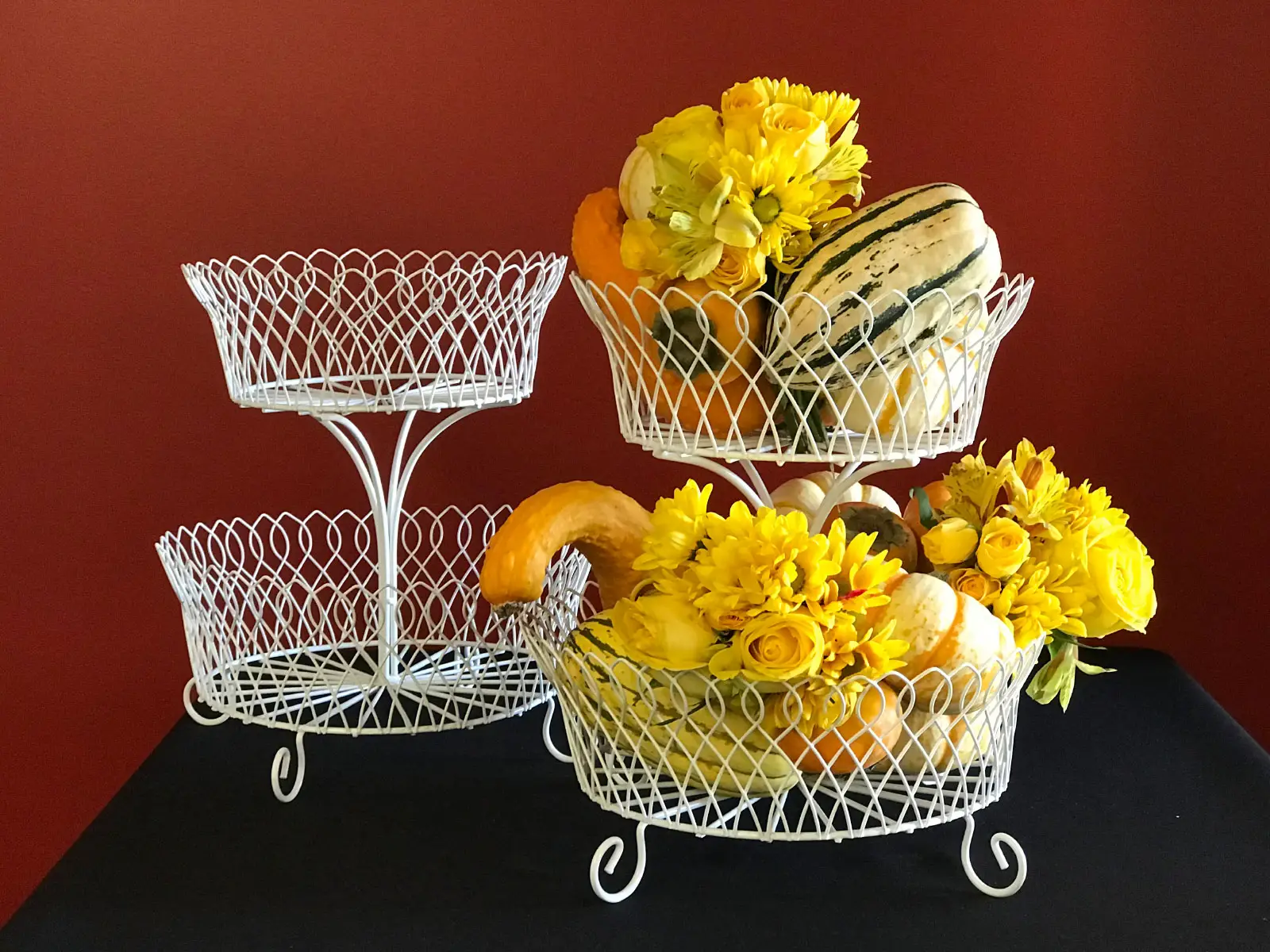 Several wax vegetable centerpieces including squash and pumpkins with flowers in white baskets