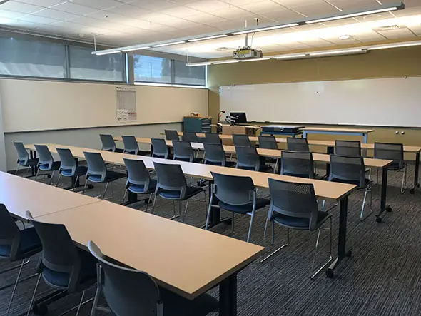 Several rows of tables and chairs in a classroom with a room-wide whiteboard in the Oregon City campus' Industrial Technology Center