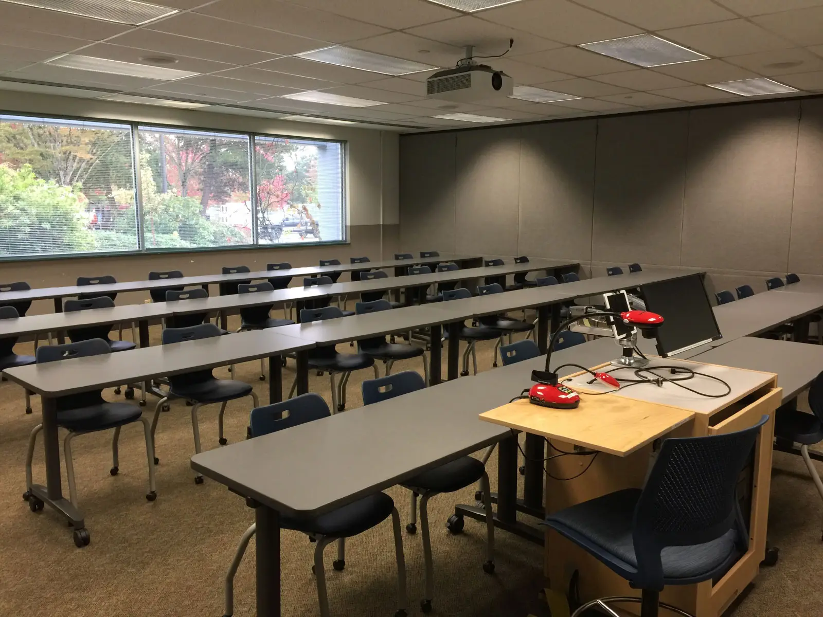 Rows of chairs and tables in front of a podium and projector in classroom W112 on the WIlsonville campus