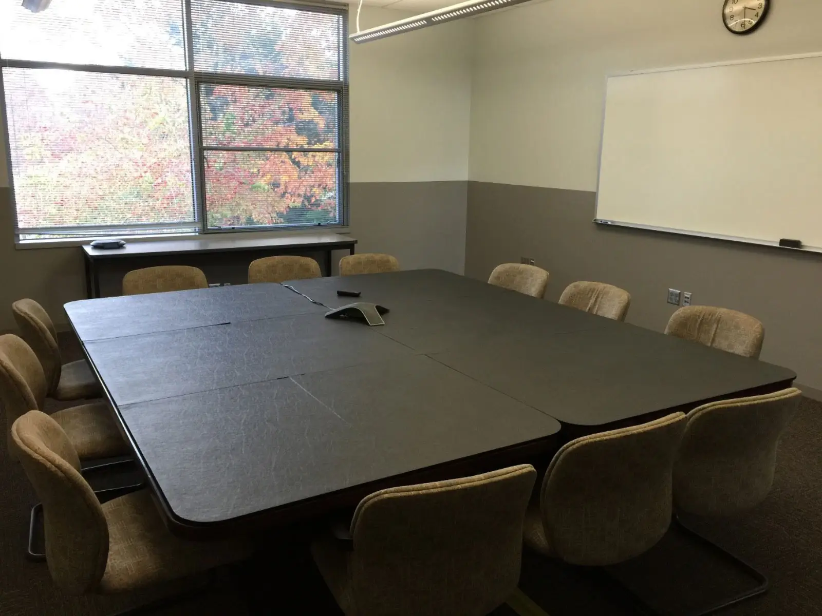 Conference room with 12 chairs and a table with center phone, white board on the wall and window in classroom W207 on the Wilsonville campus