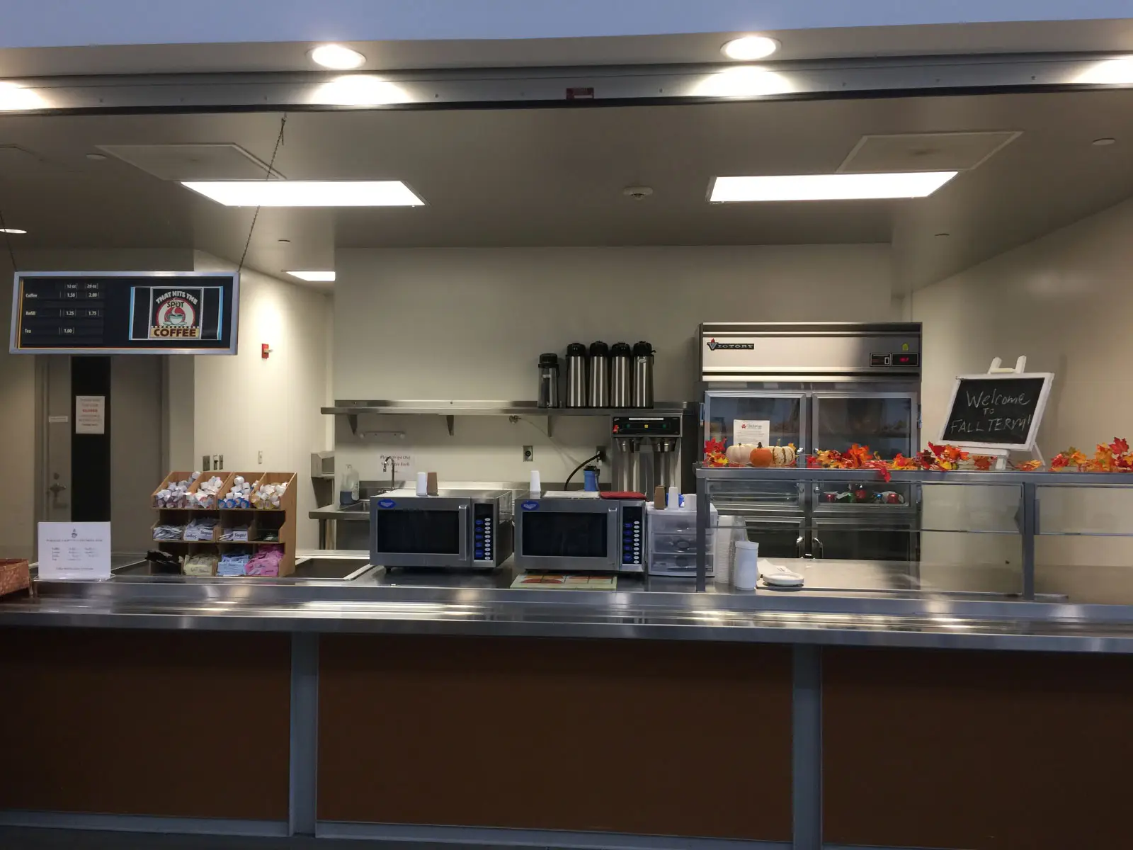 The front of the kitchen area with microwaves, refridgerator, counter and displays of the Wilsonville campus