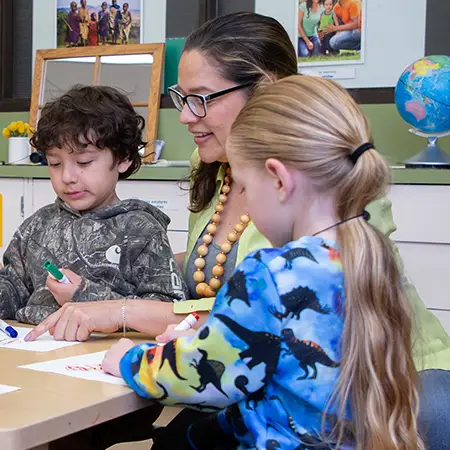 Elementary teacher shows a group of young students coloring techniques with markers.