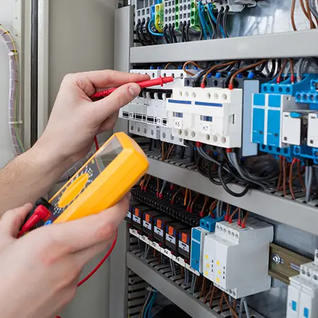 Energy systems technician testing out various hardware components with a voltage tester.