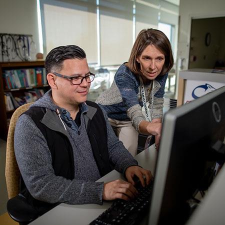 Instructor points to computer monitor as student looks on