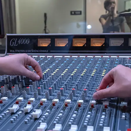 Student turns dials on a soundboard.