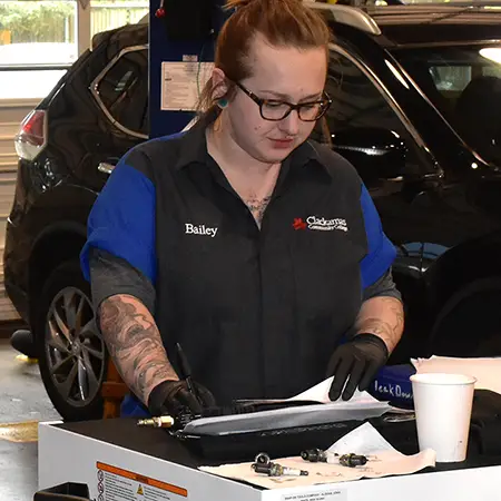 Student in the Auto Service and Repair Lab reviewing parts and paperwork.