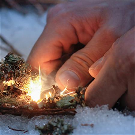 close shot of hands starting a fire in the snow